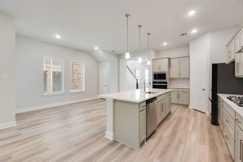 7009 Sunset Boulevard Rowlett, TX 75088 - Photo 11 of 35 a large kitchen with stainless steel appliances kitchen island a large counter top and a wooden floor