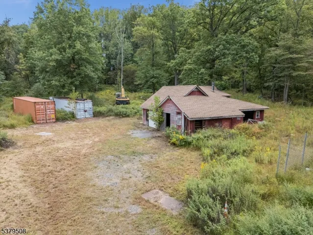 an aerial view of a house with yard and trees in the background