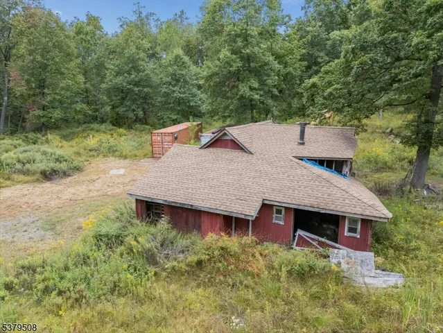 an aerial view of a house with yard and trees in the background