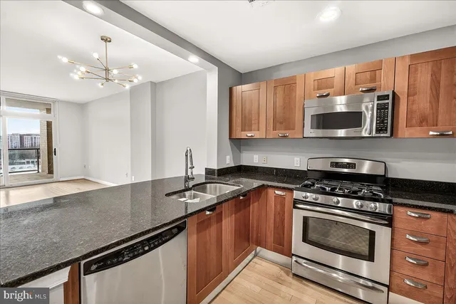 a kitchen with granite countertop a stove a sink and a microwave