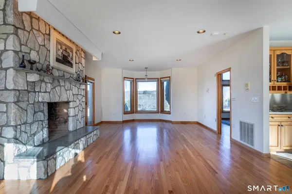 a view of an empty room with wooden floor and a fireplace