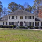 a front view of house with yard and trees in the background
