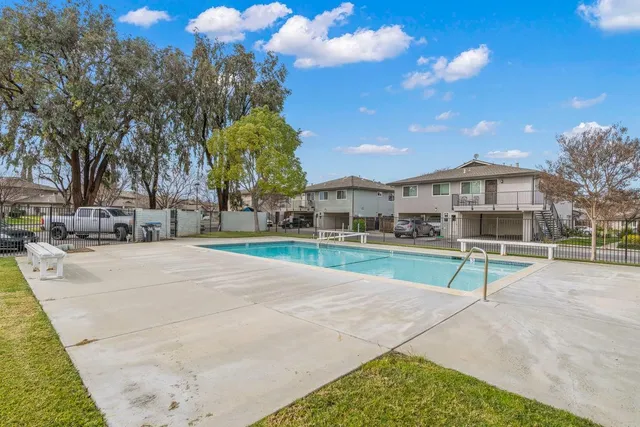a view of a swimming pool with a bench and trees around