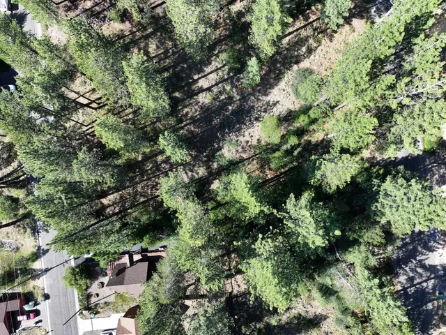 an aerial view of residential house with outdoor space and trees all around