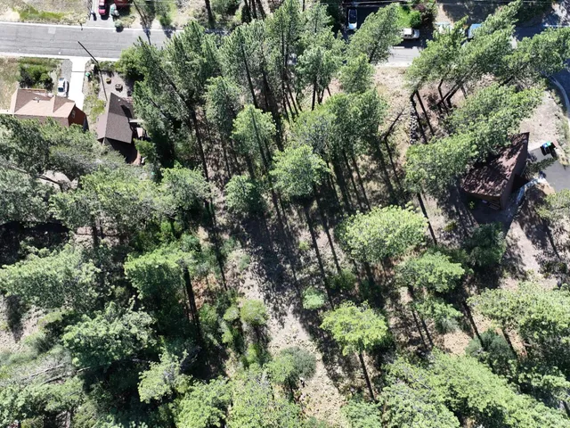 an aerial view of residential house with outdoor space and trees all around