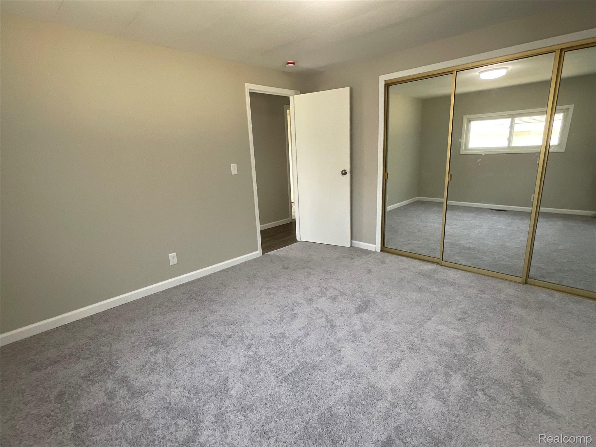 10119 Godfrey Road Bancroft, MI 48414 - Photo 25 of 47 Neutral tone wall paint, light-colored carpeting, white trim, and mirrored closet doors