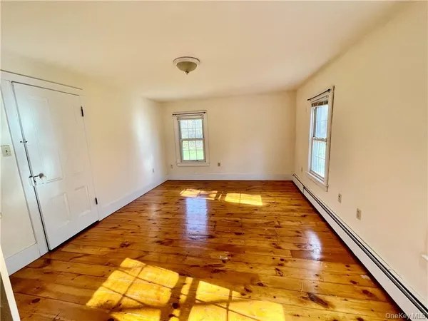 a view of empty room with window and wooden floor