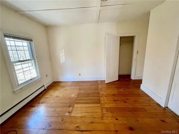 a view of an empty room with window and wooden floor