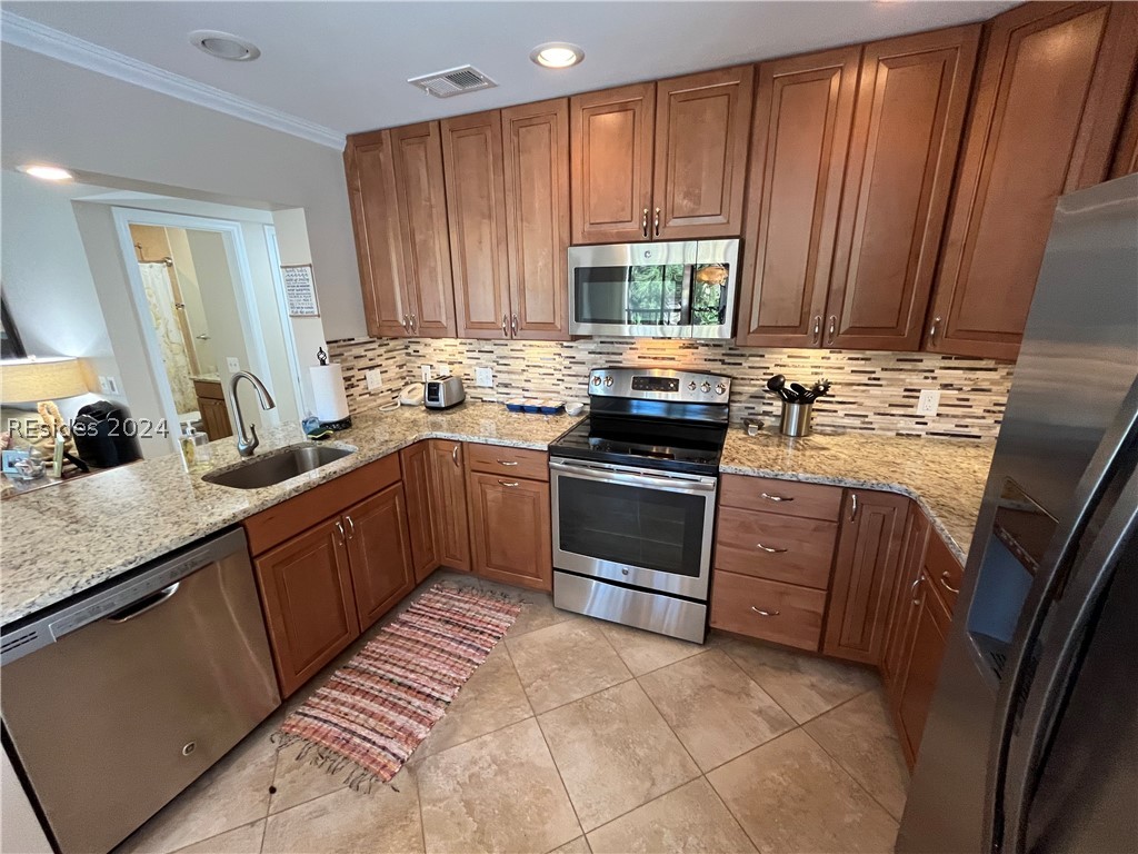 40 Folly Field Road, Unit 144 Hilton Head Island, SC 29928 - Photo 1 of 1 Kitchen featuring stainless steel appliances, tasteful backsplash, ornamental molding, sink, and light stone counters