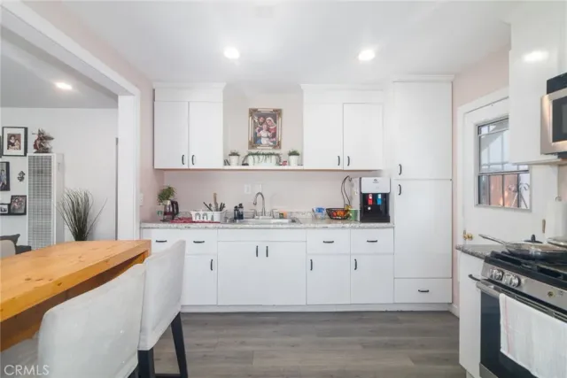 a kitchen with stainless steel appliances granite countertop a stove a sink and white cabinets