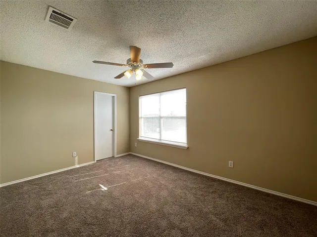 an empty room with a window and a ceiling fan