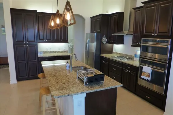 a kitchen with kitchen island granite countertop wooden cabinets and stainless steel appliances