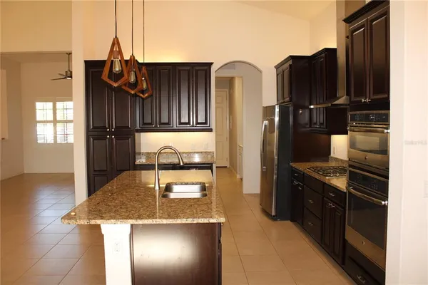 a kitchen with kitchen island granite countertop a sink a counter top space and cabinets