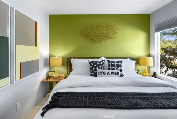 a bedroom with a bed mirror and a window