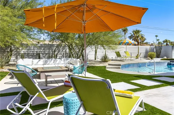 a view of a patio with table and chairs under an umbrella with potted plants