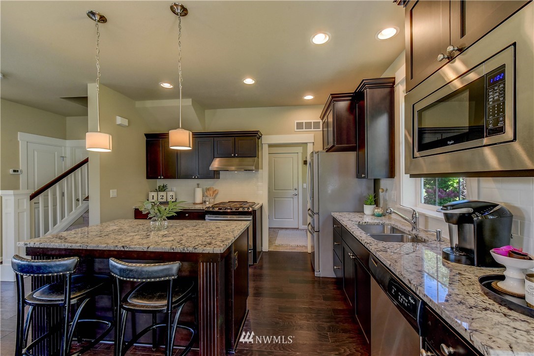 21802 38th Drive Southeast Bothell, WA 98021 - Photo 4 of 26 a kitchen with stainless steel appliances granite countertop a stove top oven a sink dishwasher a dining table and chairs with wooden floor