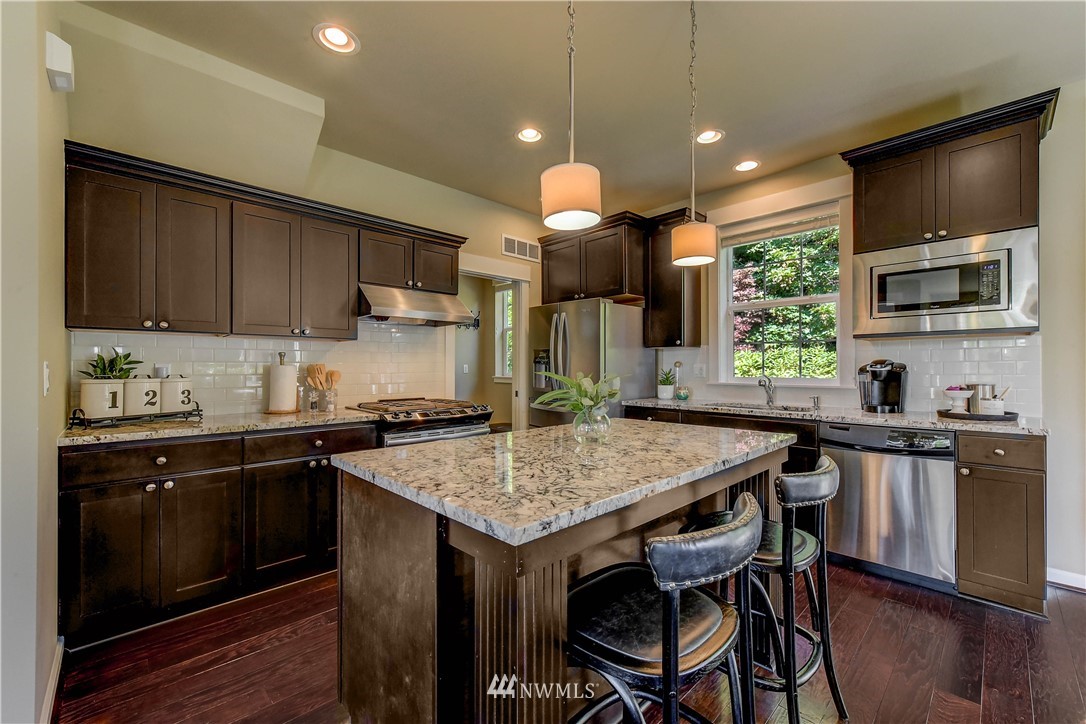 21802 38th Drive Southeast Bothell, WA 98021 - Photo 6 of 26 a kitchen with a stove top oven a sink dishwasher a dining table and chairs with wooden floor
