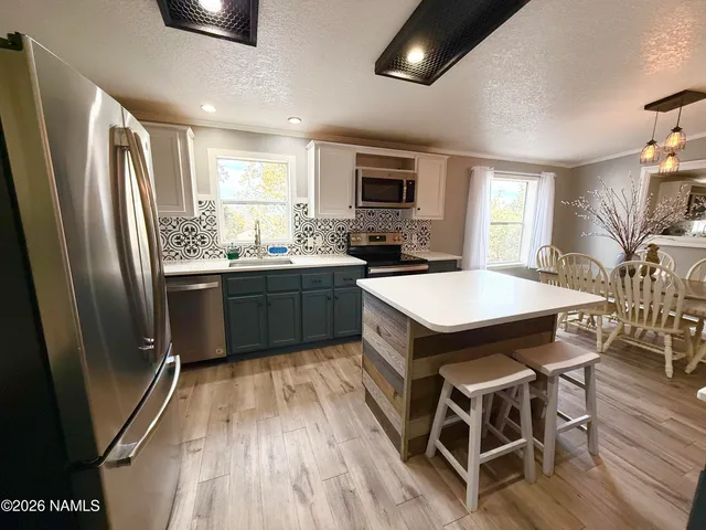 a kitchen with stainless steel appliances a sink a stove a refrigerator cabinets and dining table