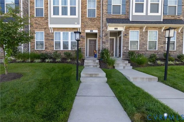 a view of a brick building next to a yard with big trees