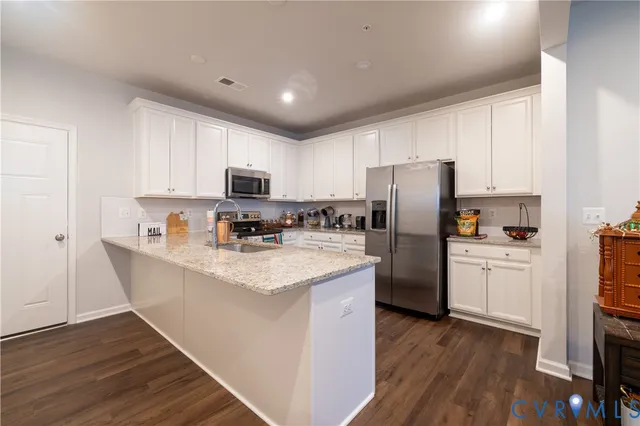 a kitchen with stainless steel appliances a refrigerator a stove a sink dishwasher and a refrigerator with wooden floor