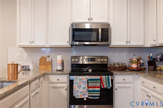 a kitchen with stainless steel appliances granite countertop white cabinets and a stove