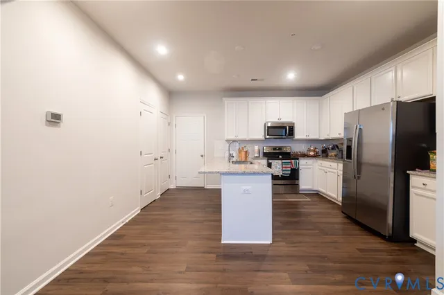 a kitchen with granite countertop a refrigerator and a stove top oven