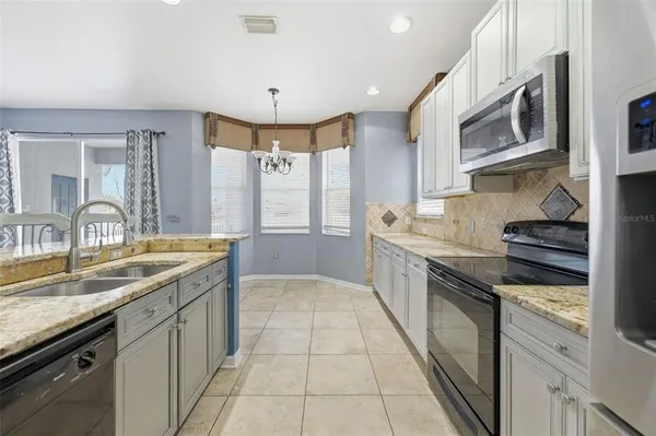 a kitchen with stainless steel appliances kitchen island granite countertop a stove a sink a dining table and chairs