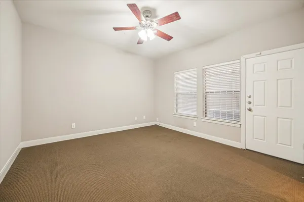 an empty room with chandelier fan and windows