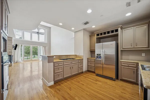 a kitchen with stainless steel appliances granite countertop a refrigerator a stove and a wooden floors