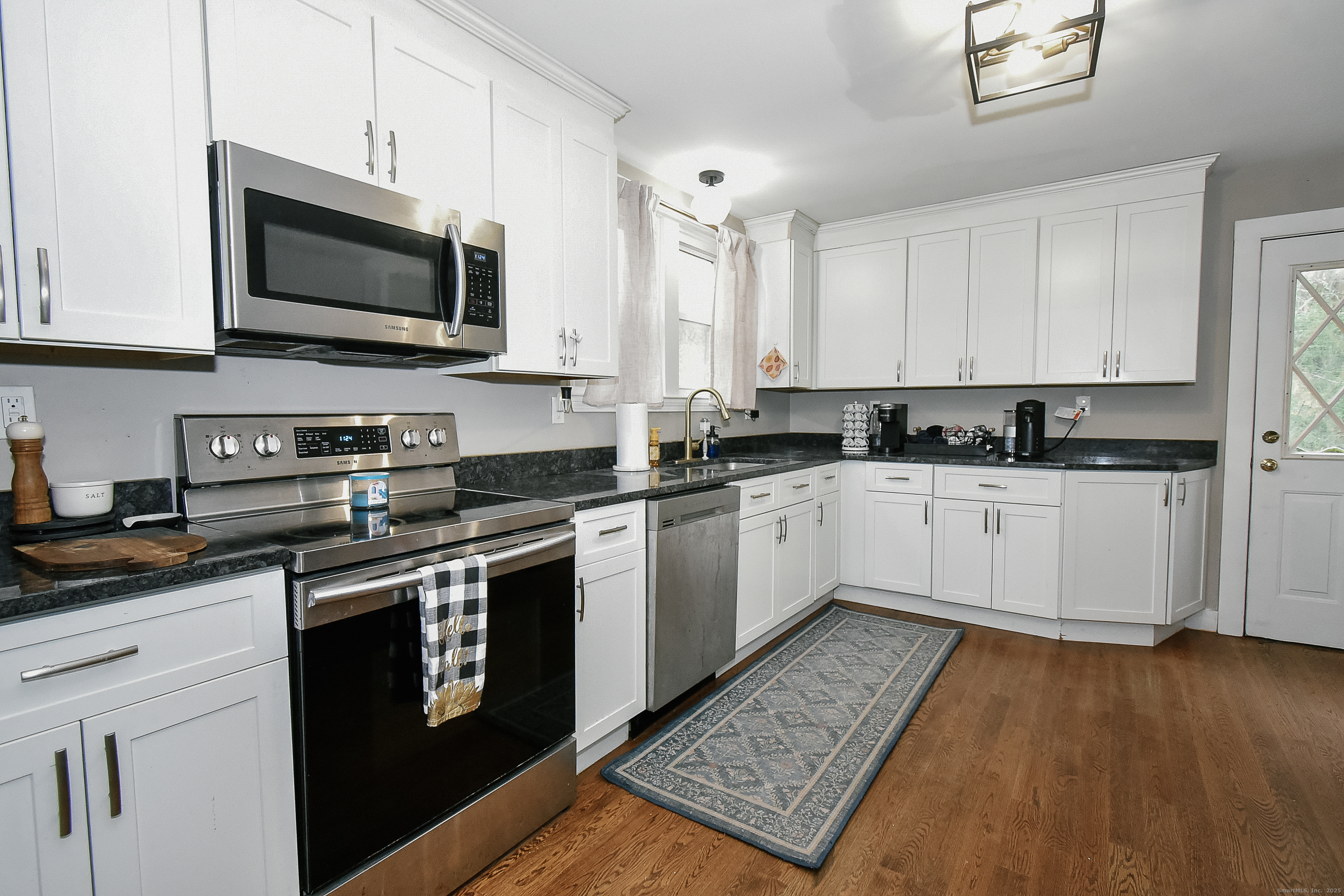 291 Hog Hill Road East Hampton, CT 06424 - Photo 6 of 24 a white kitchen with stainless steel appliances granite countertop a sink a stove a microwave and cabinets
