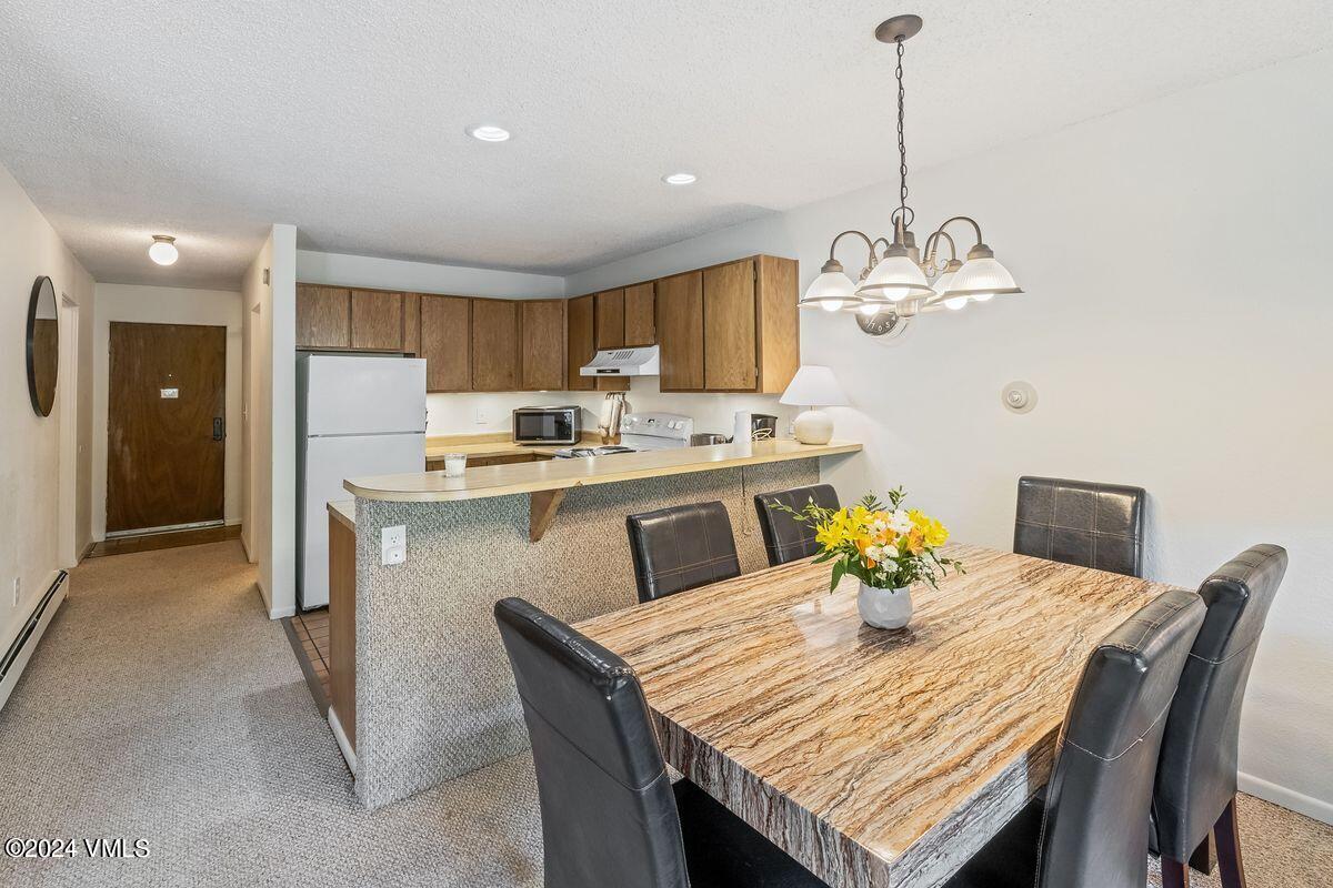 442 South Frontage Road East, Unit A205 Vail, CO 81657 - Photo 9 of 24 a view of a dining room and a kitchen with a table chairs
