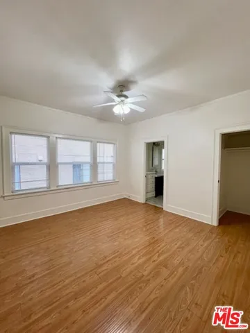 a view of an empty room with a window and wooden floor