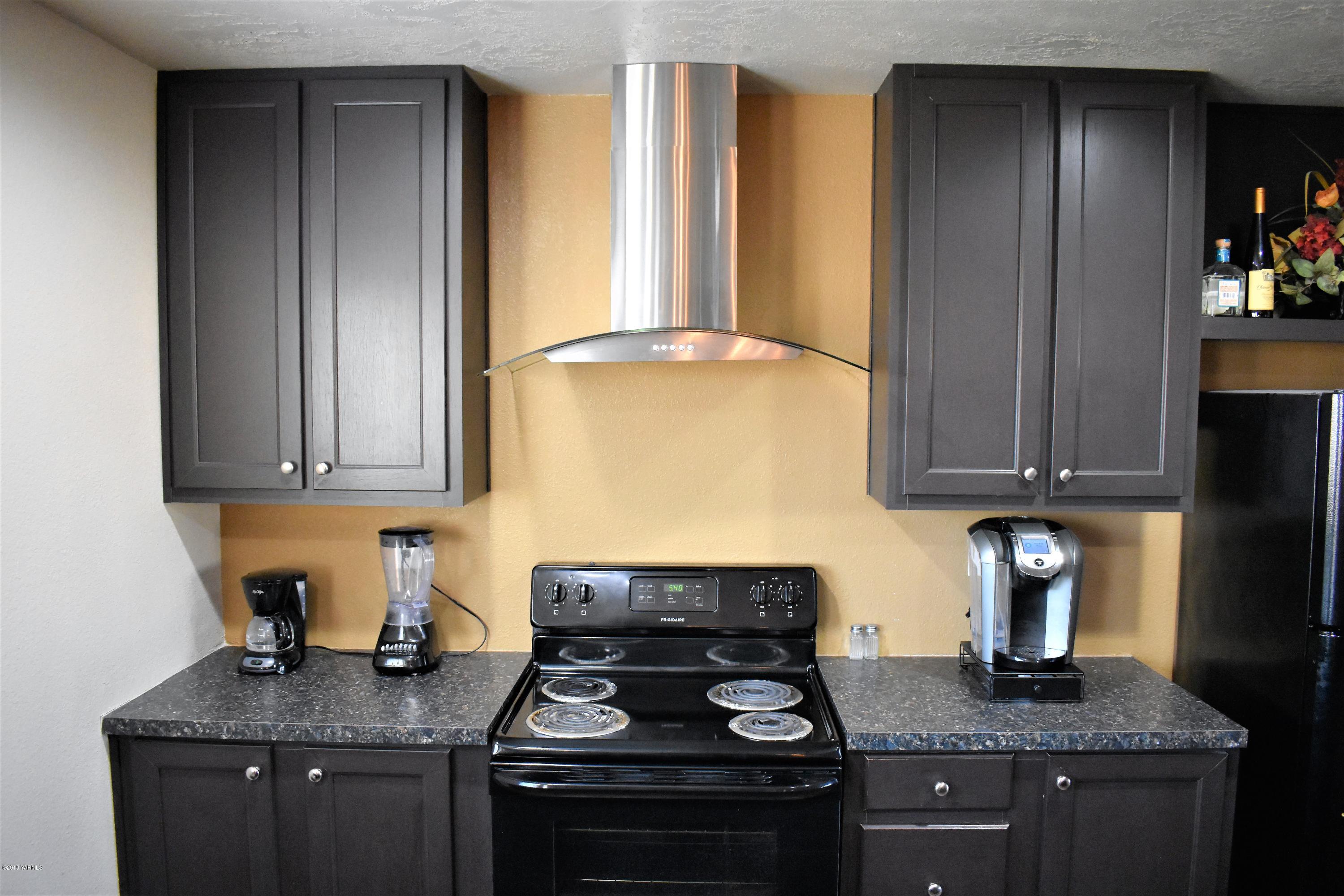 303 Hanks Road Grandview, WA 98930 - Photo 5 of 15 a kitchen with granite countertop cabinets and stove top oven
