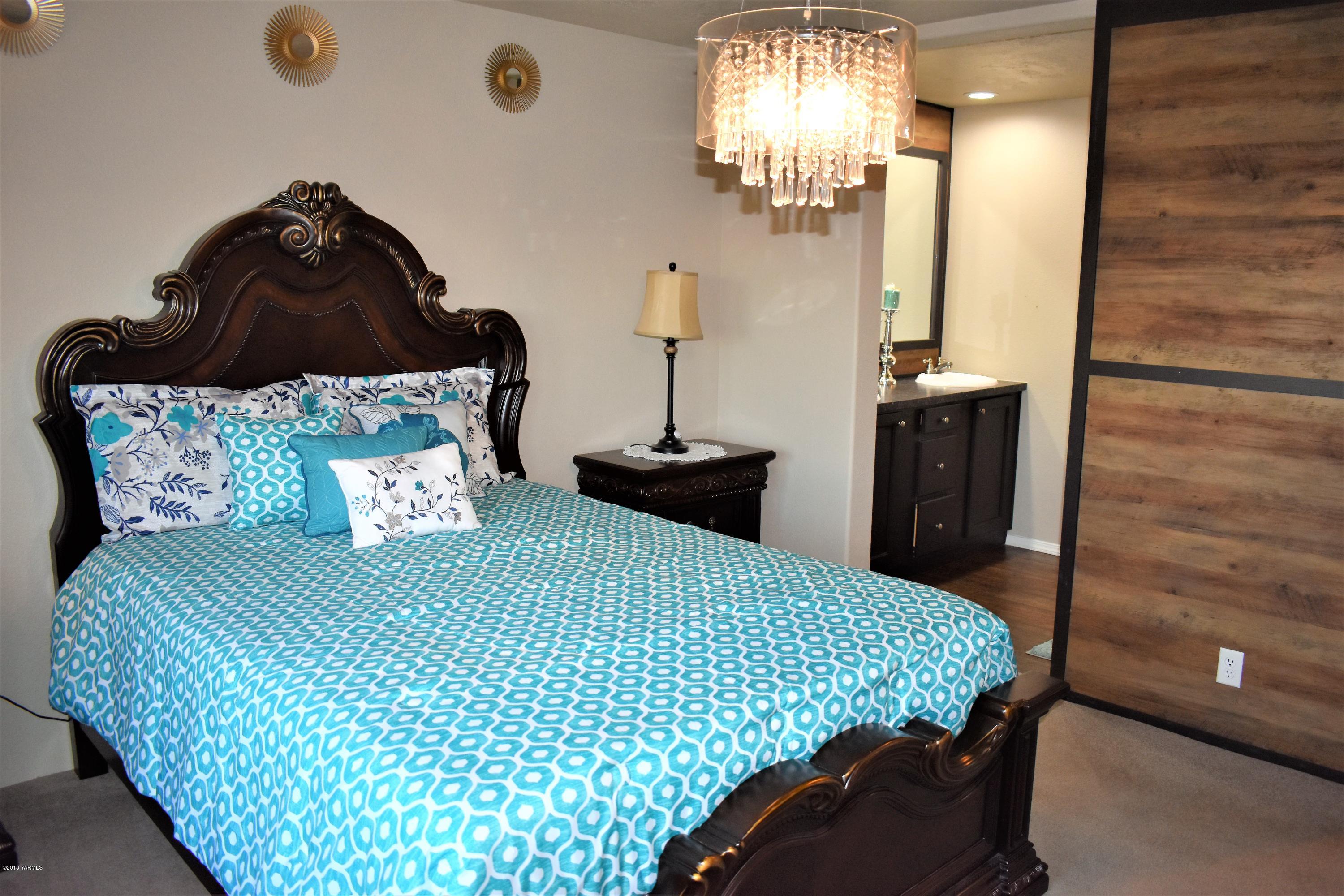 303 Hanks Road Grandview, WA 98930 - Photo 8 of 15 a bedroom with a bed and a chandelier