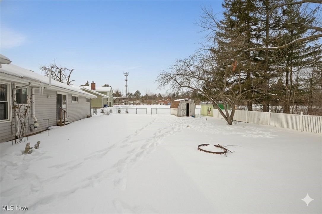 15446 Drake Road Strongsville, OH 44136 - Photo 40 of 42 Yard layered in snow featuring a fenced backyard and a shed