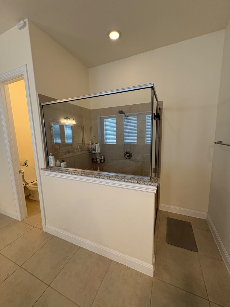 3812 Alpine Rdg Cove Leander, TX 78641 - Photo 29 of 37 A well-lit bathroom features a glass-enclosed shower and a separate water closet.
