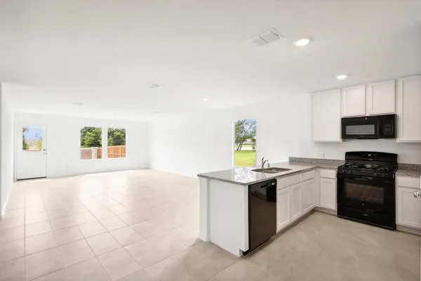 a kitchen with stainless steel appliances granite countertop a stove a sink and a microwave
