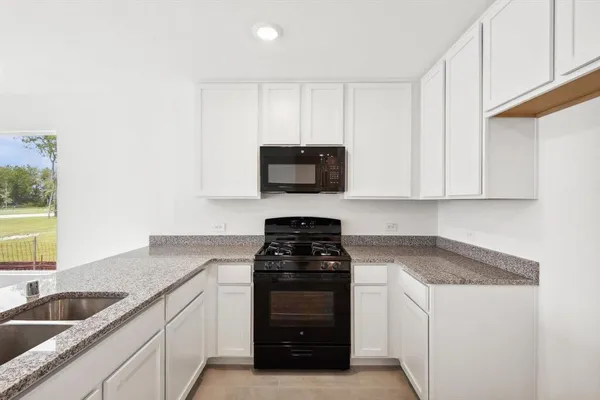 a kitchen with granite countertop white cabinets and black appliances