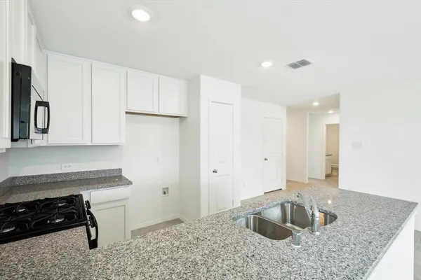 a kitchen with granite countertop a sink a stove and a refrigerator