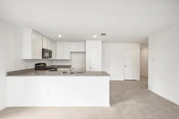 a kitchen with stainless steel appliances granite countertop a sink a stove a refrigerator a microwave and cabinets