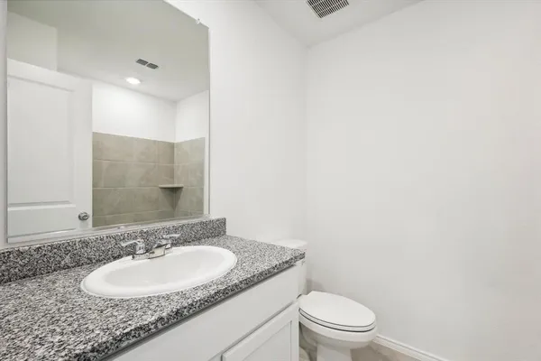 a bathroom with a granite countertop sink toilet and a mirror
