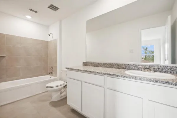 a bathroom with a granite countertop sink a toilet a mirror a bathtub and shower