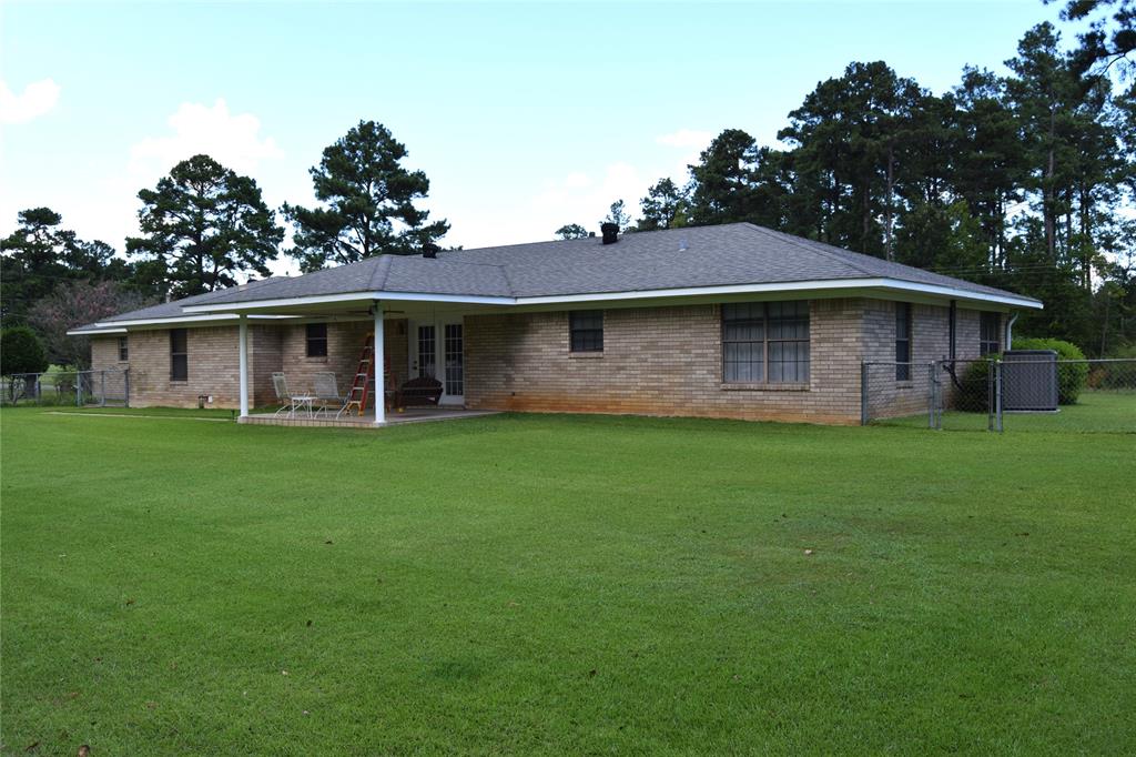 Brick exterior with a covered patio, French doors, and an expansive lawn