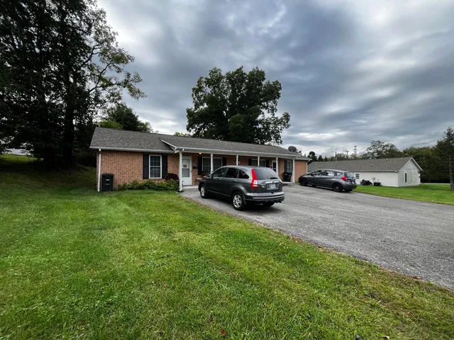 a car parked in front of a house next to a yard