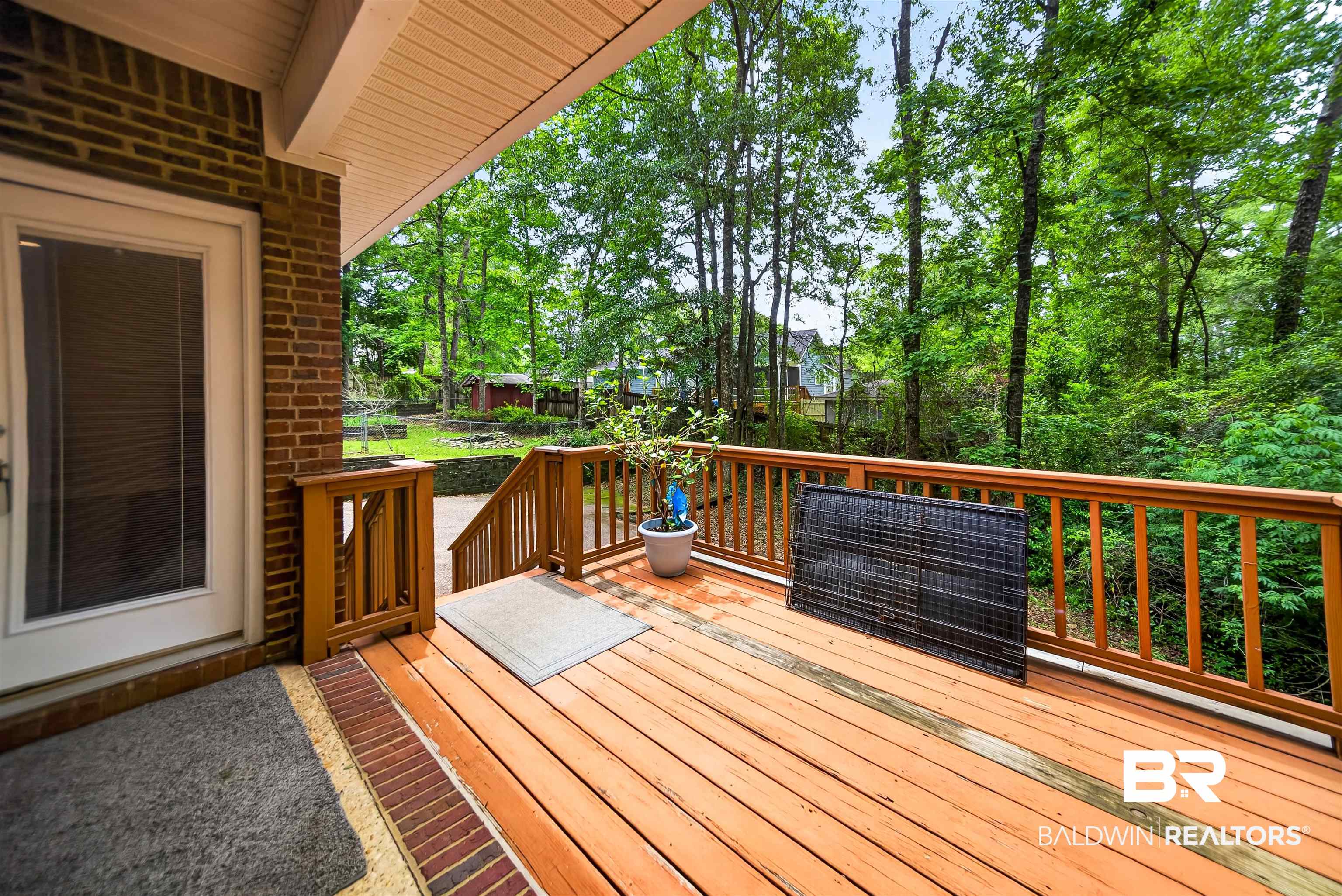 5913 Antoine Road Mobile, AL 36693 - Photo 26 of 33 Expansive wood deck with a natural wood finish, featuring a full-glass panel door, brick exterior accents, and wood railings