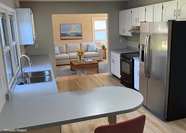 a living room with stainless steel appliances furniture a rug and a window