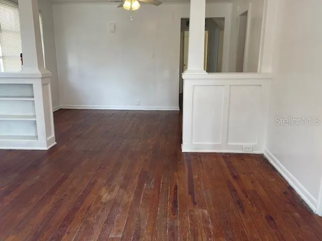 a view of an empty room with wooden floor and a window