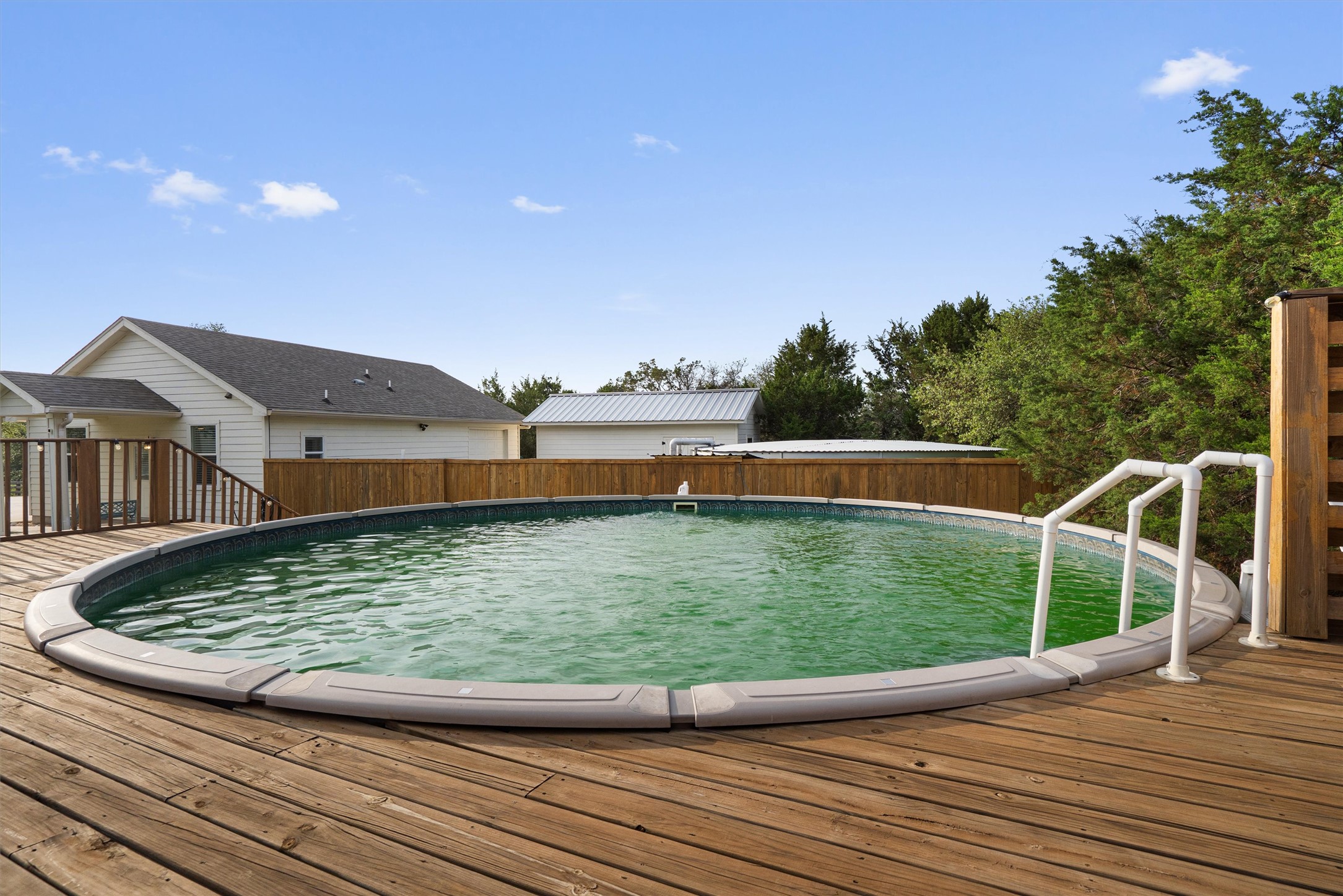 13105 Rooster Springs Road Austin, TX 78737 - Photo 33 of 38 The property features an above-ground pool integrated into a wooden deck, complete with white handrails for entry