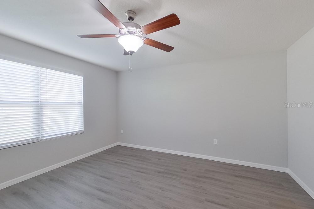 8731 Southwest 44th Court Ocala, FL 34476 - Photo 14 of 20 an empty room with wooden floor fan and windows