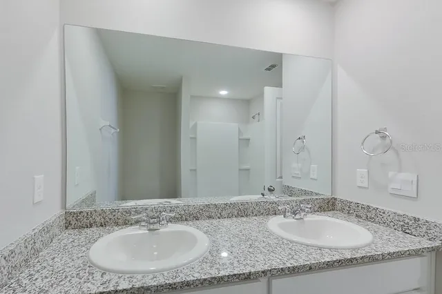 a bathroom with a granite countertop sink and a mirror
